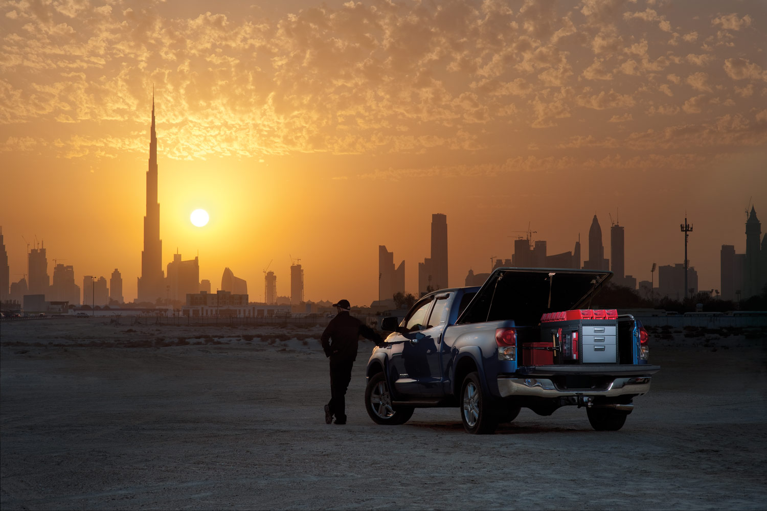 Worker's blue pickup truck with modul-system racking in a desert facing a sunset